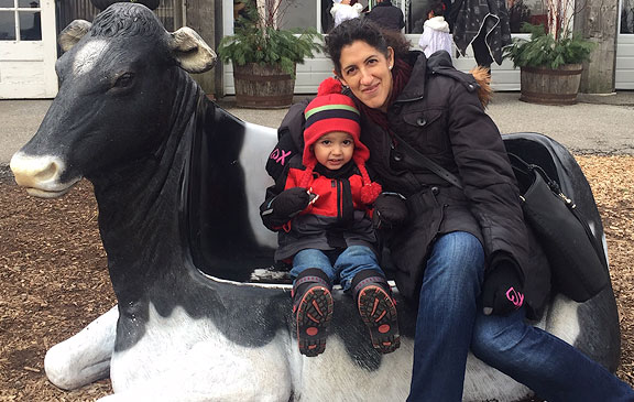 A woman sitting on a cow statue with her toddler son