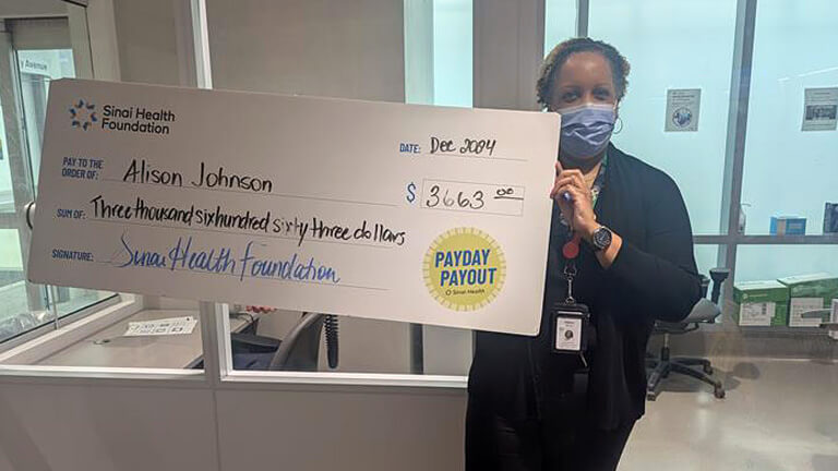 Photo of Alison Johnson holding the winning Payday Payout cheque