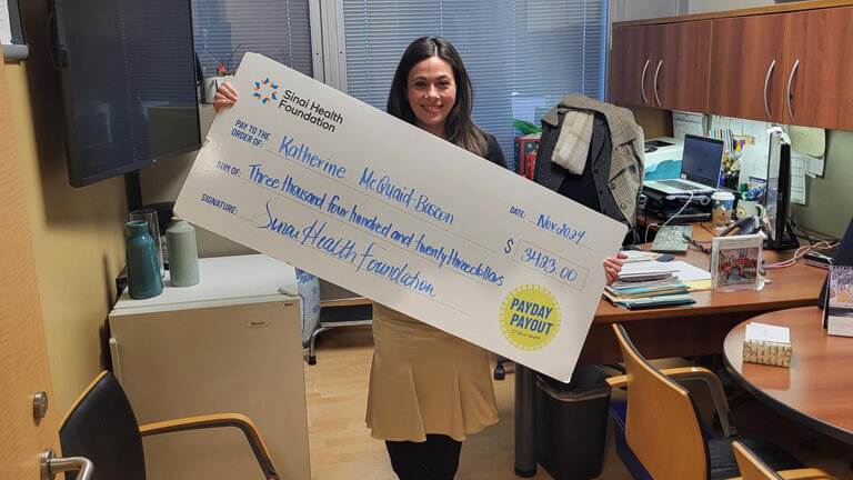 Photo of Katherine McQuaid-Bascon holding the winning Payday Payout cheque