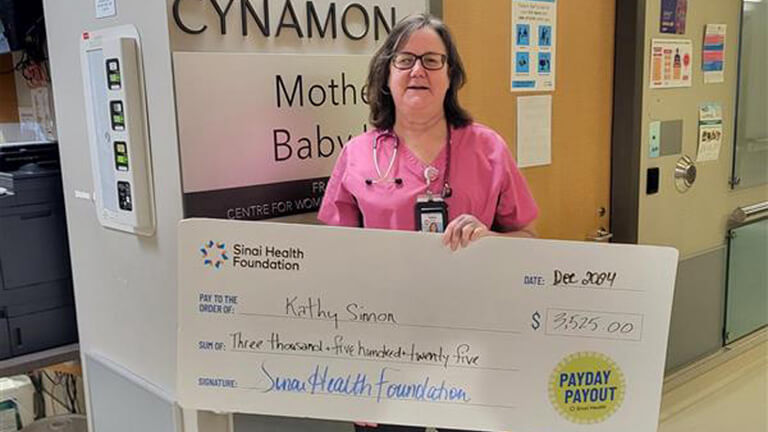 Photo of Kathy Simon holding the winning Payday Payout cheque