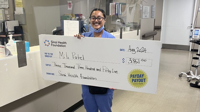Photo of Mili Patel holding the winning Payday Payout cheque