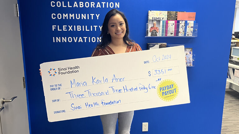 Photo of Maria Karla Anor holding the winning Payday Payout cheque