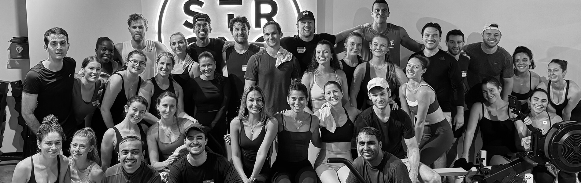 A large group of smiling people posing together in a gym set